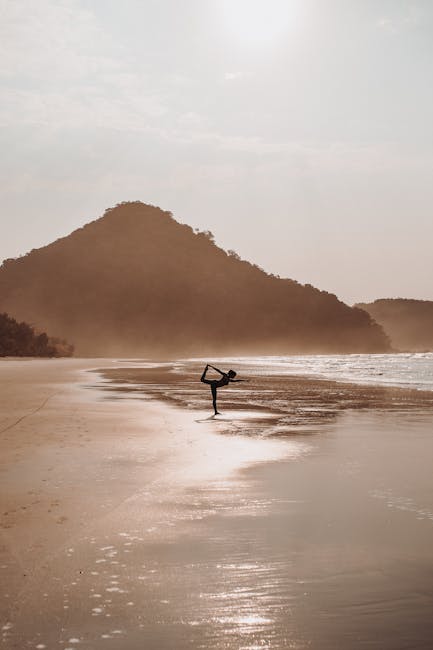 Woman performing a calm yoga pose by a lake during sunrise